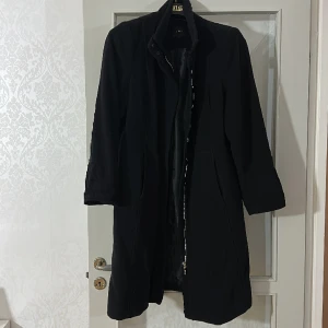 Kappa svart kappa från lindex fin och i bra skikt men skedjan funkar inte.  - En fin kappa i storlek 46 från Lindex. Materialet är fin och fräch men skedjan funkar inte. 