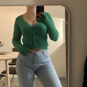 Grön ribbad topp - Grön topp från H&M. Som ny. Storlek XS. Strecthig, går att använda som cardigan också. 