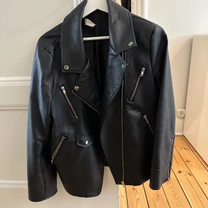 Skinnjacka - Oversized skinnjacka med guld-detaljer. NA-KD x Donna Romina. Använd men i fint skick! 
