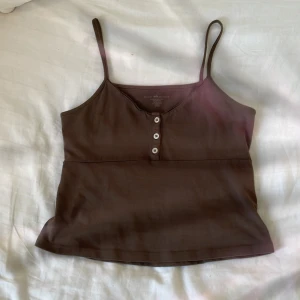 Gulligt Brunt linne - Jättesött brunt linne från brandy melville i storlek one-size, men passar XS-S💘 Den har vita små knappar på framsidan som man kan knäppa upp. Fråga om frakt.