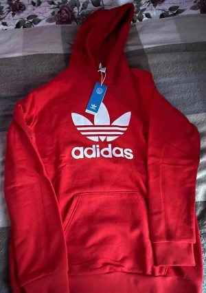 Röd Adidas Hoddie  - Säljer en helt ny Adidas hoodie med prislapp på.   Storlek M-L