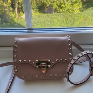 Valentino Garavani väska! - En super fin valentino väska i en ljusrosa färg. Väskan är i väldigt fint skick, inget slitage vid kanter eller liknande. Det synbara slitaget är några repor på framsidan (men tror ev de går att få bort). Detta är dock inget som är märkbart vid andvändnin