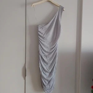 Klänning med en axel - En fin klänning i mjukt och tunt tyg med ett axelband. Ljugrå i färgen. Storlek S ifrpn HM. 