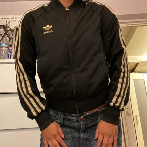 Adidas kofta  - Guld svart adidas kofta. Köpare står för frakten annars möts jag upp i Sthlm 💕