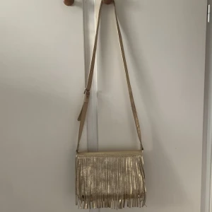 guldig fin fransväska - Superfin väska med fransar i guld, köpt second hand så färgen skiftar på fransarna🧡