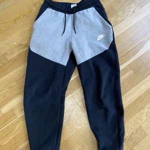 Nike tech byxor  - Nike tech byxor för både män och kvinna. Grå/svart. Storlek S Bra skick men ett litet ihop sytt hål vid benet så syns knappt. Köpare står för frakten❤️