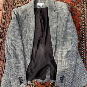 Kavaj - Grå kavaj i fint skick, inte jättemycket använd men lite. Inga synliga hål eller skador av annat slag. Axelkuddar är insydda i den. 