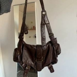 Brun röd y2k väska  - Y2k väska som man vara under armen eller över axlarna, rymlig och i bra skick! 