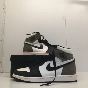 Jordan 1 High Mocha - Hej! Säljer ett par mycket fina och helt oanvända Jordan 1 High Mocha som passar perfekt till en person som vill ha ett par mycket fina skor. Jag har tyvärr inget kvitto men allt annat ingår. Boxen  är också skadad på lite olika sider.  Dm för fler frågor
