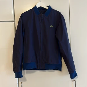 Lacoste marinblå sommarjacka  - Snygg och trendig Lacoste sommarjacka. 