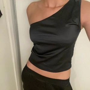 Svart satin top - Snygg svart festlig satin topp från Gina Tricot. Stretchigt tyg passar flera storlekar.  Aldrig använd!