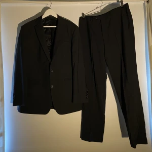 Oscar Jacobson Helsvart Kostym  - Hej, säljer en mycket elegant helsvart kostym från Oscar Jacobson. Strechig och bekväm. Nypris närmare 5000kr. Bra skick utan fläckar eller dyklikt. Storlek 52 vilket motsvarar Large. Perfekt inför studenttider. Hör av dig! Pris inte hugget i sten.
