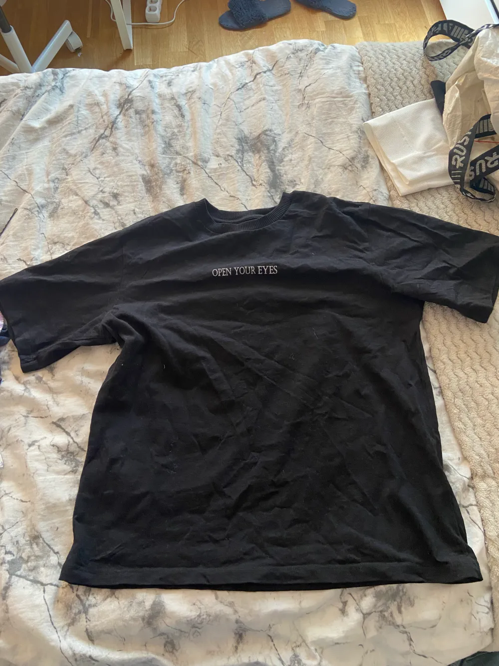En svart t-shirt med tryck och text, kostar 30kr+20krfrakt . T-shirts.