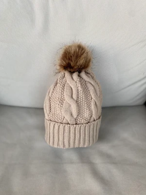 Fodrad mössa med pom - Sprillans ny vinter mössa med pom🙌. Mysig med foder inuti som gör den perfekt till höst/ vinter❄️.  100% bomull så man svettas inte och huvudet får andas.  Storlek: One size  Färg: Mörkbeige  Antal kvar: 2 st