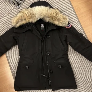 Vinterjacka - Svart ”Montebello” Canada Goose jacka. Jackan är i bra skick med väldigt lite milda fläckar. Kvittot finns ej kvar men det är en äkta vara som köpts hos NK för några år sedan. Jackan har inte används många gånger och luktar fräsch än idag! Inga hål/skador