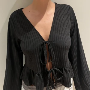 PCANNY LS CARDIGAM D2D - Svart topp med knytning fram. Toppen är bara testad, säljer pga känns förlusten för mig. Tröjan är L men känns som en S/M. Kostade 400kr och säljer för 350kr. Funkar bra att mötas och att frakta!🤍finns fler bilder på tröjan i mitt flöde!