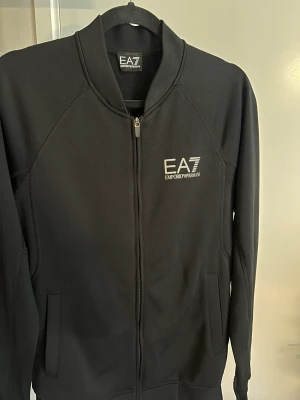 Emporio Armani Kofta - Hej! Säljer nu en kofta/träningströja från Emporio Armani i storlek M. Trycken är i reflex och syns i mörker riktigt snyggt! Jag köpte denna från Zalando m  Hör av dig vid frågor