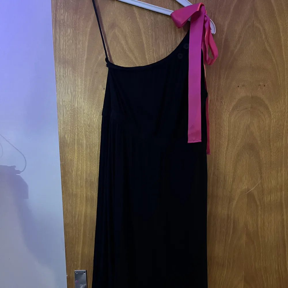 En kort svart klänning me ett rosa band på ena axeln. Säljer denna klänning då den inte är min stil o ja aldrig använder den. Den är använd 2 gånger så den e i bra skick. Vet dock inte vilken storlek men tror de är typ Xxs. Klänningar.