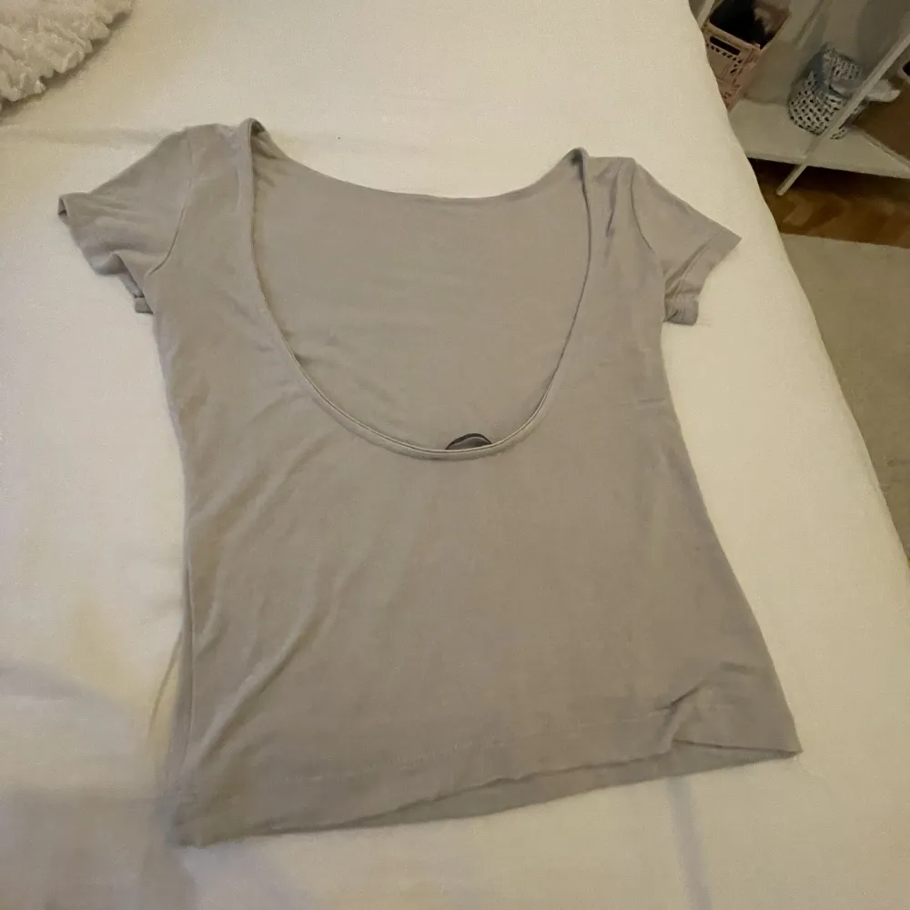 Säljer min supersnygga T-shirt med öppen rygg! Köpt från missäy men står it storlek🩷Är som en xs! Är grå beige och har inga defekter!. T-shirts.