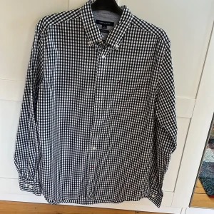 Rutig svartvit skjorta - Oanvänd, som ny. Tommy Hilfiger, köpt i usa. Mycket stilig. Kan mötas i eslöv eller Lund, annars står köparen för frakt.