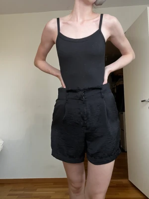Svarta shorts satin - Shorts med hög midja. Stor i storleken. Man kan ha ett skärp i dem. Köpt second hand. 