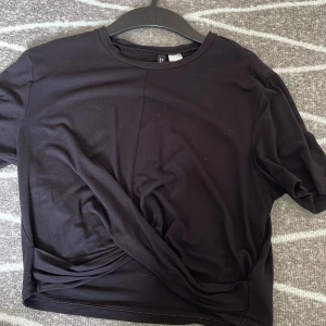 Knuten topp - En svart topp från H&M med en ”knutning” vid magen som gör den till en magtröja. Väldigt fin och pasaar till allt.