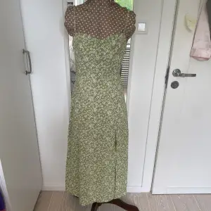 Grön blommig klänning med slit. I stl XS men passar även S