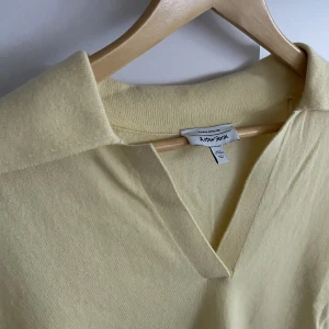 Stickad tröja med öppen krage - En stickad gul tröja med öppen krage och stickade volanger vid änderna av ärmarna. Köpt från & Other Stories för 1-2 år sedan. I perfekt skick, precis som ny. Använd 1-2 gånger. Tyckte den var väldigt söt men den har inte riktigt passat mig och min stil💛