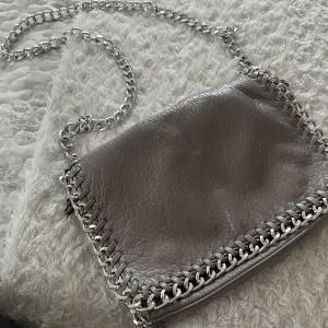 Väska - Grå väska. Ganska långt kedjeband. Lite rostig på få ställen som inte syns tydligt. Medelstor. 