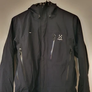 Haglöfs vind/regnjacka i strl M - Svart Haglöfs skal/regn/friluftsjacka i strl M. Inköpt aug 2019 för en vandring och har tyvärr inte använts sedan dess. Jackan är i 2 lagers GORE-TEX. Vind och vattentät med många funktioner. Webbkvitto kan uppvisas. Kan skickas mot fraktkostnad.