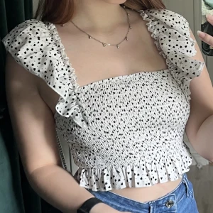 Prickig topp - Vit topp med svarta prickar i form av hjärtan! Finns tyvärr ingen lapp kvar så vet inte vilken storlek det är men skulle gissa på en xs eller s. Går att ha både som en vanlig topp och som off shoulder🤩