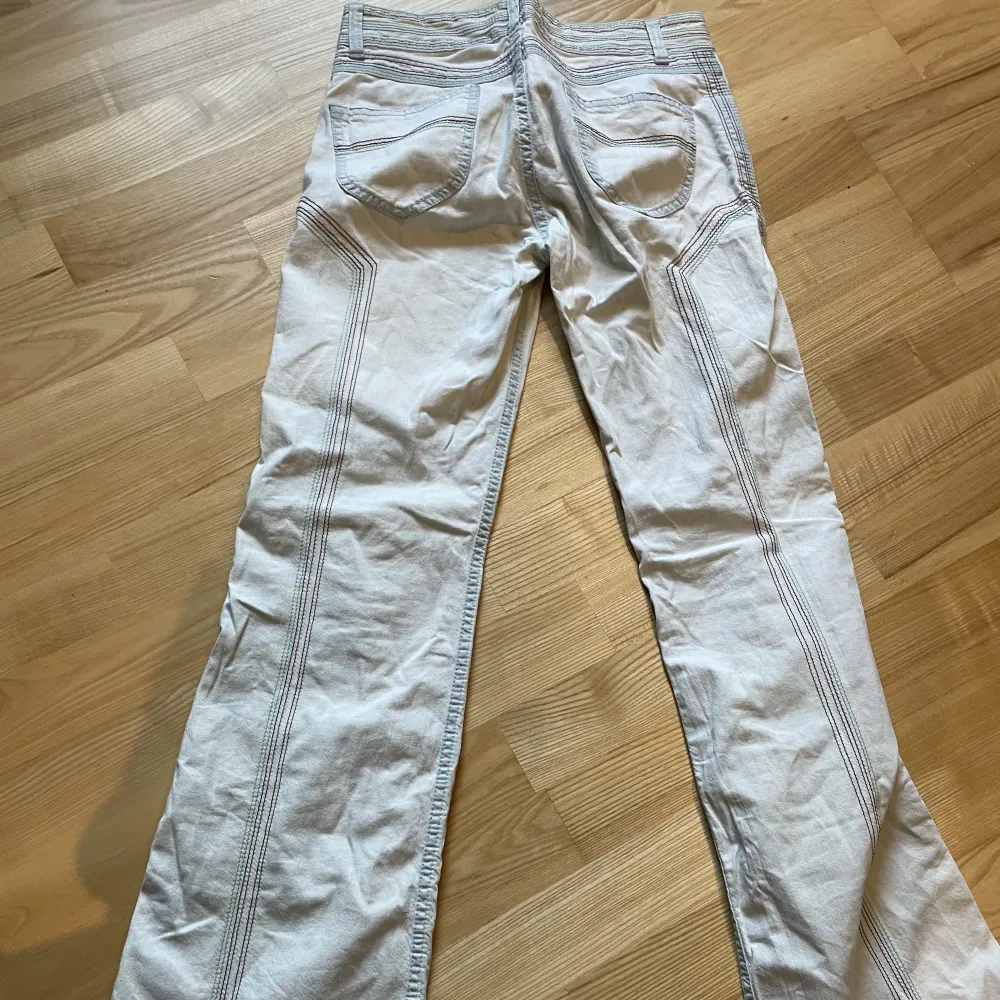 Vita utsvängda jeans med regnbågsfärgade stygn! Från DKNY-jeans!. Jeans & Byxor.