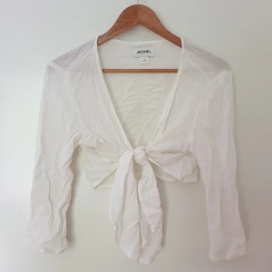 Somrig croppad knutblus  - En semigenomskinlig magtröja/knytblus från Monki i 100 % viskos. Mycket bra skick.