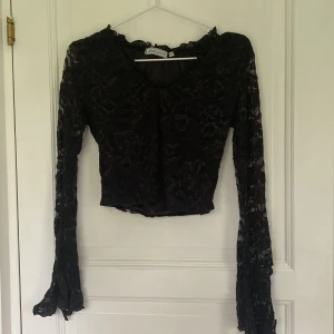 Glittrig spets top - Svart glittrig spetstopp med blommmönster, är bred i armarna och har en slit. Är rätt liten i armarna för mig som brukar ha s så passar nog bra npgon som brukar ha xs. Köpt på second hand 
