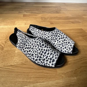 Sandaler leopard - Slingback sandaler i leopardmönstrat skinn. Resår bakom hälen. Kanske 80/90-tal. Rymliga, för bredare fötter.
