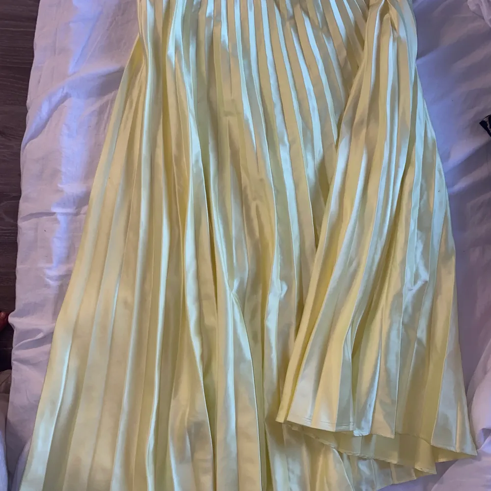 En fin plisserad kjol i satin ifrån zara, använd ett fåtal gånger, den är mycket gulare i verkligheten vilket är svårt att få på bild . Kjolar.