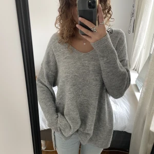 Grå stickad tröja - Stickad tröja med v-ringning från h&m med slits på sidan.