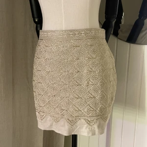 kort kjol - En kort beige kjol med ”guldigt” mönster på framsidan💓 aldrig använd🫶 skriv till mig om fler bilder önskas🥰