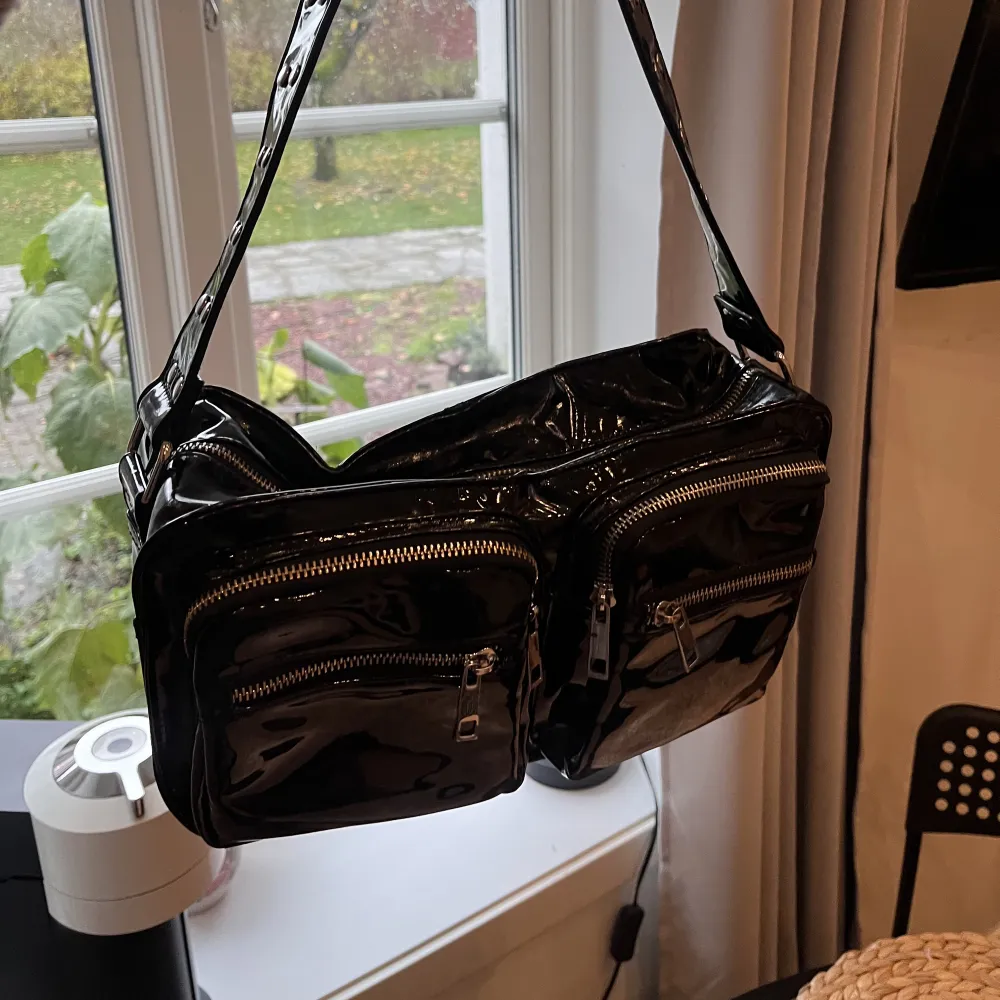En svart lackväska från Noelle, rymlig och bra storlek på axelväska, får plats mycket i den. Har en liten innerficka. . Accessoarer.