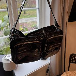 En svart lackväska från Noelle, rymlig och bra storlek på axelväska, får plats mycket i den. Har en liten innerficka. 