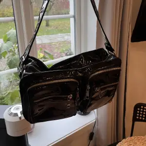 En svart lackväska från Noelle, rymlig och bra storlek på axelväska, får plats mycket i den. Har en liten innerficka. 