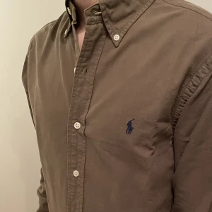 Ralph Lauren skjorta  - En fantastisk fin Ralph Lauren skjorta, helt oanvänd. Färgen är Khaki, dvs lite olivgrön med lite bruna toner. Den är i strl S med slim fit.  Priset kan diskuteras vid snabb affär