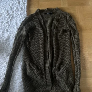 Grön kofta från Vero Moda. Storlek Xs - Säljer denna gröna kofta från Vero Moda i storlek XS. Koftan är lite längre och i en väldigt fin grön färg. Koftan är i väldigt bra skick men fickan har släppt på ena sidan (se bild). 