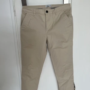 Byxa - Mouli kostymbyxor i färgen Beige. Storlek 30