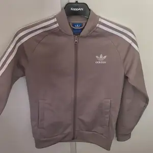 En hoodie från adidas i barnstorlek men passar även en xs, grå/rosa/beige färg som inte finns att köpa längre.