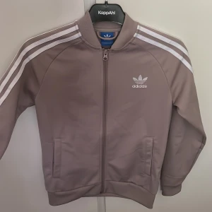 Adidas hoodie - En hoodie från adidas i barnstorlek men passar även en xs, grå/rosa/beige färg som inte finns att köpa längre.