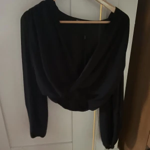 Söt blus från NLY ONE - Fin svart blus från NLY ONE, resår i midjan och vid handlederna. Djup v-ringning