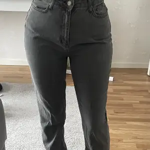 Ett par gråa jeans med slit som är i storleken 38 