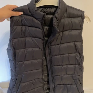 Svart väst - En enkel och tunn väst. Sitter väldigt fint på då den är figurformad. Den är i ett jättebra skick. 