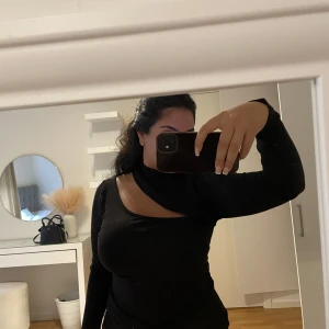 Svart ribbad topp med öppning - Denna svarta ribbade toppen är så snygg till en utgång. Öppningen går ända till ryggen. 